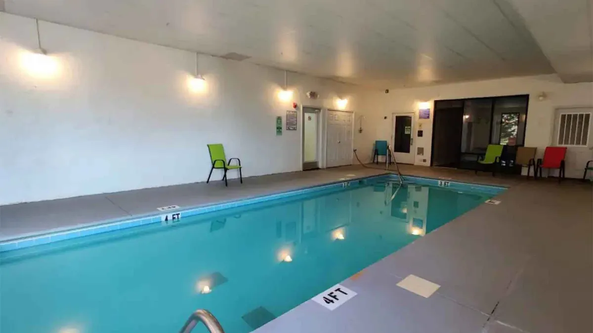 This vibrant interior pool area is filled with colorful chairs and bright lighting, inviting guests for a swim. The pool is clearly the focal point, with poolside seating and a cheerful, active atmosphere.