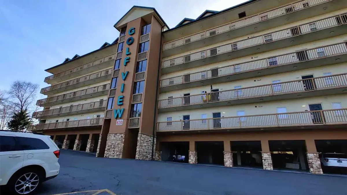 The image displays the exterior of the resort building, featuring balconies with scenic views and prominent signage. The welcoming facade suggests easy access to recreational activities and establishes a sense of community within the neighborhood.